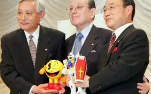 Masaya Nakamura (au centre) lors de la fusion de Namco avec Bandai, en 2005. Il est décédé en 2017 à l’âge de 91 ans (Crédit Photo : AFP/KAZUHIRO NOGI)
